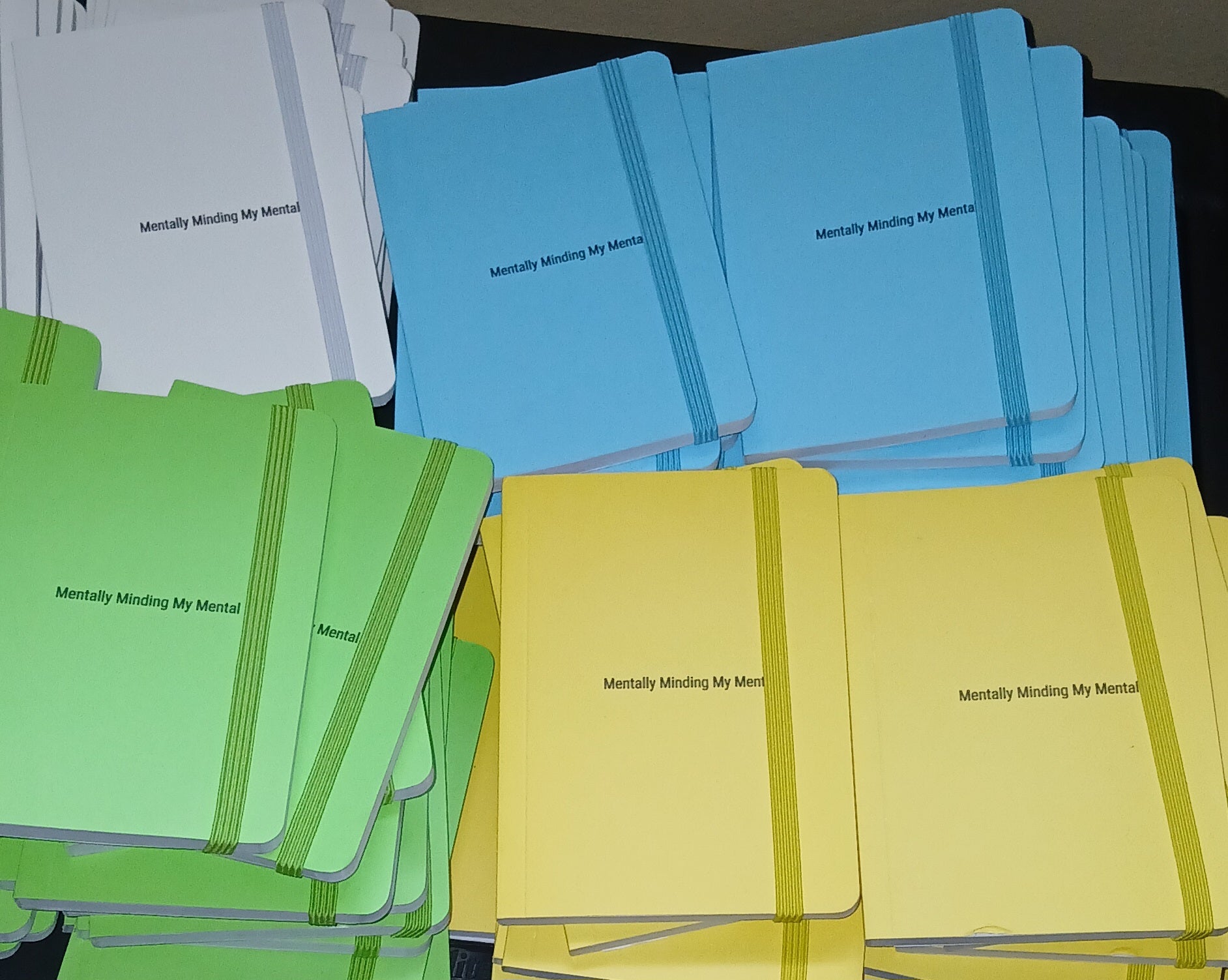 Stacks of notebooks in blue, green, and yellow with text on a dark surface.